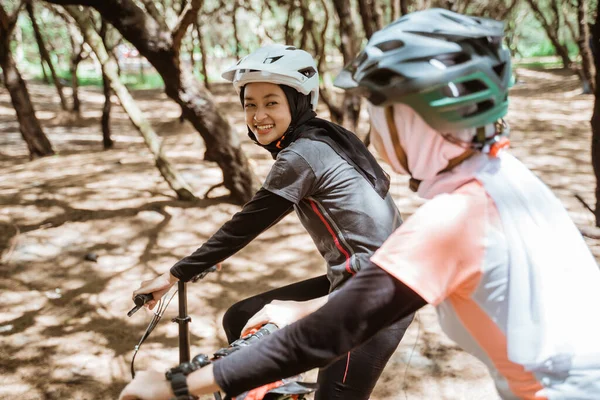 Mladá muslimka smích a chatování při jízdě na kole s přáteli — Stock fotografie