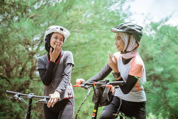 Dvě mladé muslimky klábosení při jízdě na kole — Stock fotografie