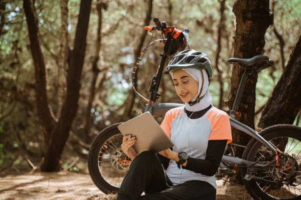 Otururken ve dinlenirken dijital tablet kullanan örtülü kadın