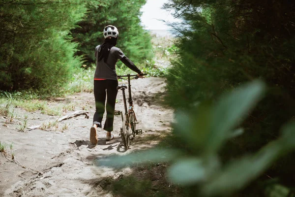 Dişi bisikletçi, dik yollardan geçerken bisiklete rehberlik eder.