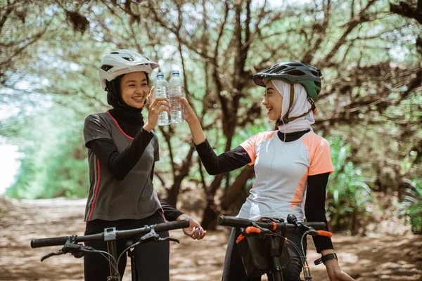 İki genç kadın ellerinde bir şişe maden suyu tutuyordu.