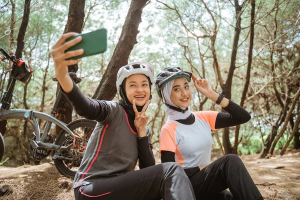 İki peçeli kız selfie ve V işareti cep telefonu kullanıyor.