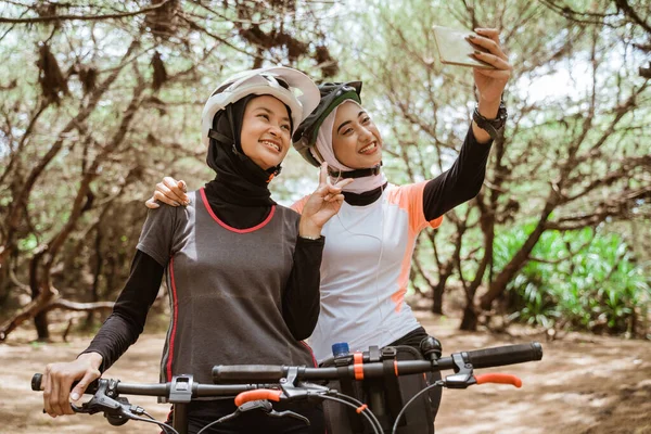Dvě ženy selfie s V podepsat gesto ruky při jízdě na kole — Stock fotografie
