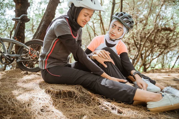 Arkadaşlarıyla parkta bisiklet sürerken peçe takan yaralı bir kadın.