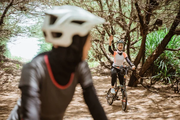 Bisikletli Müslüman bir kadın arkadaşına el sallıyor.