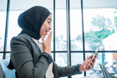 Telefonuna bakarken tesettürlü bir iş kadını.