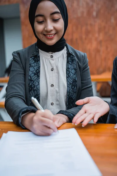 Mujer de negocios musulmana firmar un contrato con su pareja durante la reunión de oficina —  Fotos de Stock