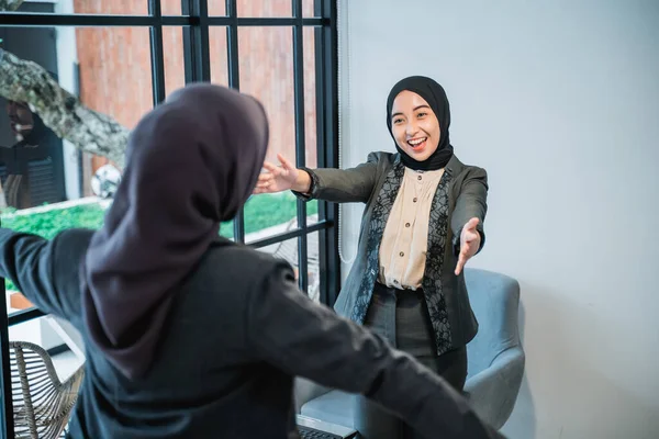 Musulmana saludando y abrazando a su pareja mientras se reúne en la oficina —  Fotos de Stock