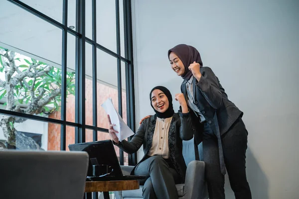 Happy muslim businesswoman raise their arm while looking at the business report — стоковое фото