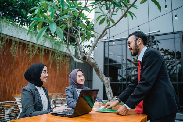 Businessman at meeting with his two female muslim employee — стоковое фото