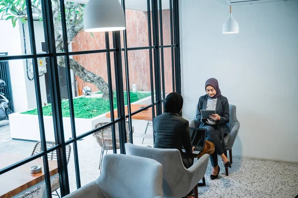 Muslim female worker sitting in sofa and using tablett pc — Fotografia de Stock