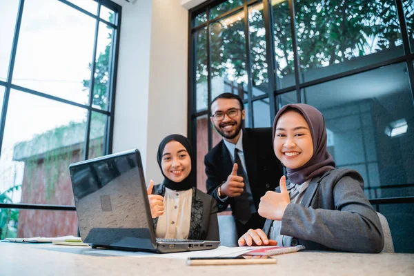 Business team showing thumb up while sitting at the office — стоковое фото