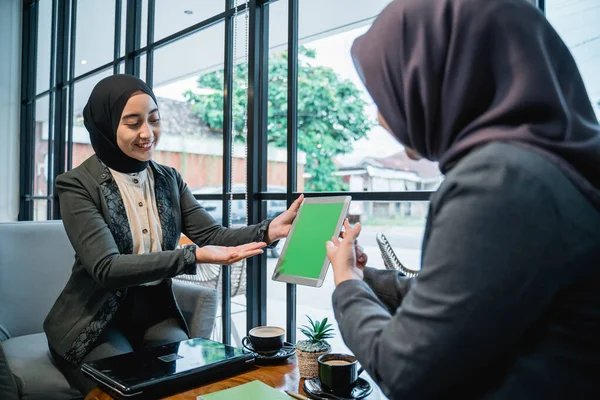 Мусульманська жінка-працівник обговорює зі своїм колегою, використовуючи планшет — стокове фото