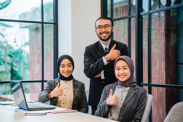 Business team showing thumb up while sitting at the office — Stockfoto