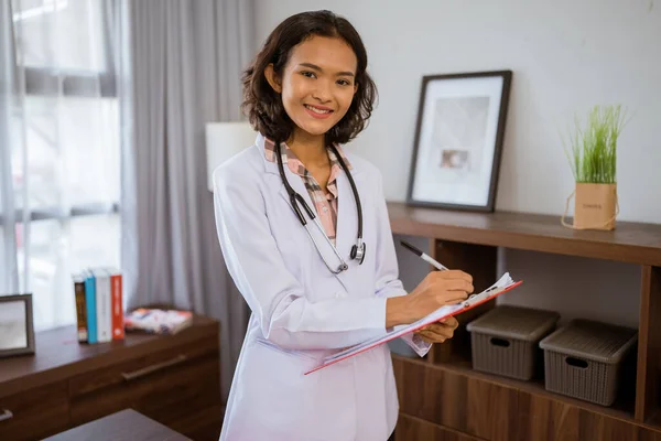 Young Asian Female Doctor Standing While Writing Using Clipboard Clinic — Zdjęcie stockowe