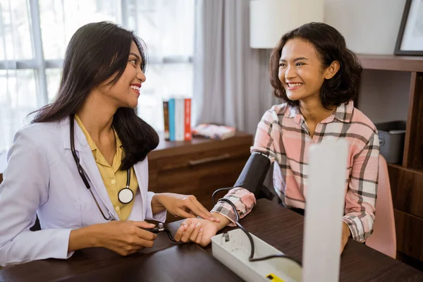 Female Doctor Chatting Female Patient While Using Sphygmomanometer While Sitting — Stockfoto