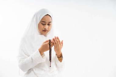Asian woman wearing ihram clothes praying with prayer beads on isolated background