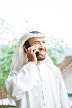 young man in a turban is calling using a mobile phone while smiling