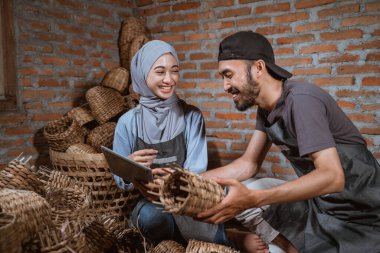craftswoman in veil chatting with craftsman while using a tablet in a brick house