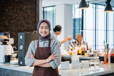 beautiful asian muslim woman crossed arm while standing in front of coffee shop
