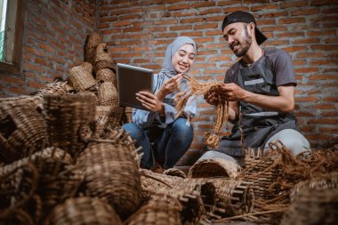 woman in veil using tablet with craftsman showing woven rope in brick house