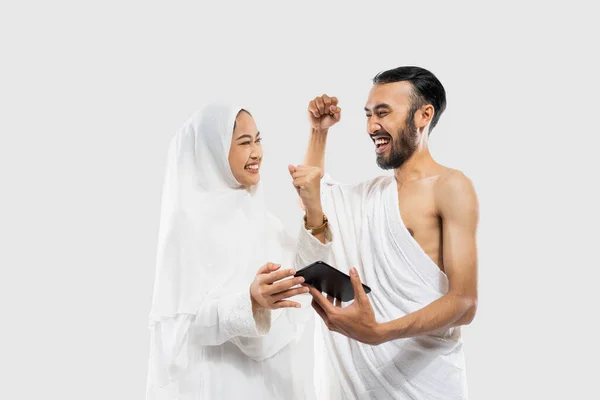 Happy Couple Wearing Ihram Clothes Looking Video Using Smartphone Clenched — Stok Foto