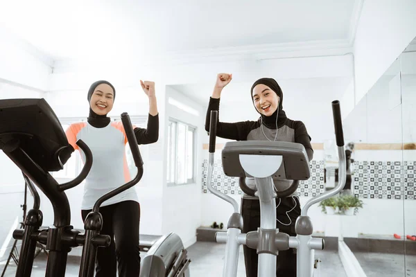 Excited Beautiful Woman Hijab Gym Exercising Friend Static Elliptical Cycle — стоковое фото