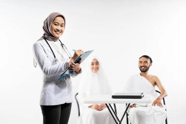 Smiling Veiled Doctor Carries Clipboard Prospective Congregation Background — Zdjęcie stockowe