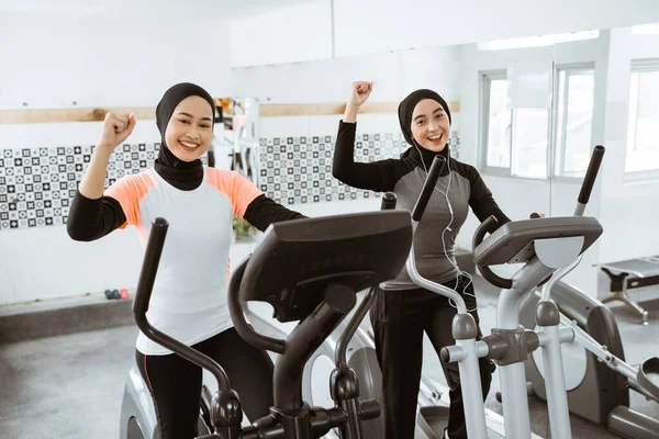 Excited Beautiful Woman Hijab Gym Exercising Friend Static Elliptical Cycle — Fotografia de Stock