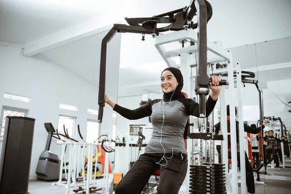 muslim asian woman using chest press machine during fitness at the gym
