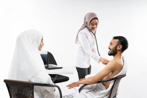 Doctor Using Stethoscope Examining Pair Prospective Pilgrims Sitting Room — Stockfoto