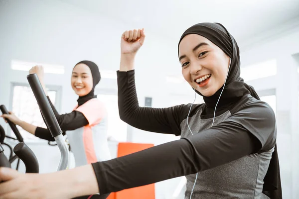 Excited Beautiful Woman Hijab Gym Exercising Friend Static Elliptical Cycle — Stockfoto