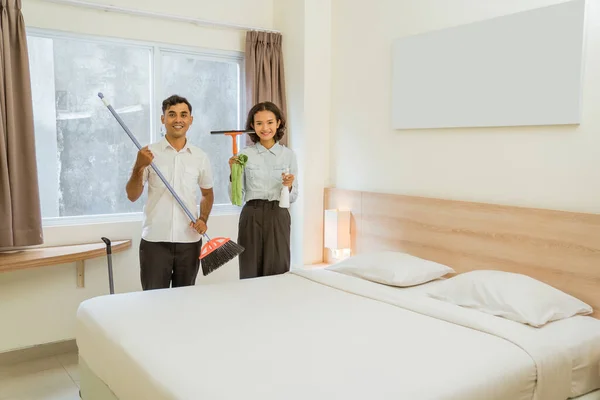 Two Cleaning Staff Holding Cleaning Tools Standing Bed Hotel Room — стоковое фото