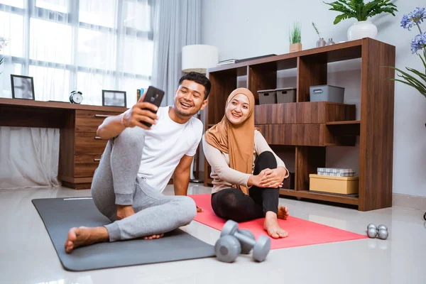 Muslim Couple Using Mobile Phone Together Exercising Home — Stockfoto
