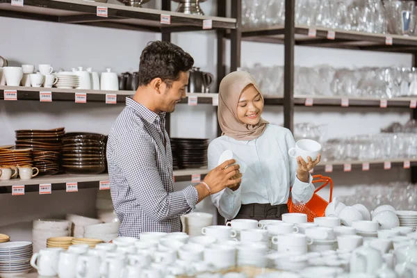 Young Muslim Woman Holding Cup While Selecting Crockery Her Male — Fotografia de Stock