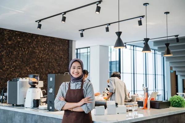 beautiful asian muslim woman crossed arm while standing in front of coffee shop