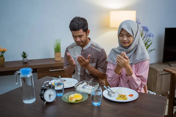 一对穆斯林夫妇早起去吃萨胡尔或苏胡尔的早餐作为禁食 显示时间的前置时钟 — 图库照片