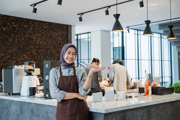 muslim waitress or owner at her coffee shop welcoming customer to her newly open shop