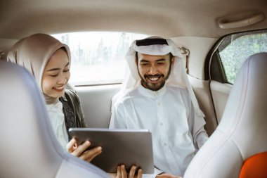 muslim business partner discussing and meeting using tablet pc presenting project while sitting on a car