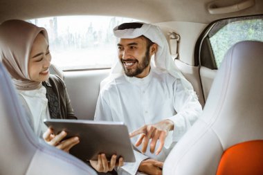 muslim business partner discussing and meeting using tablet pc presenting project while sitting on a car