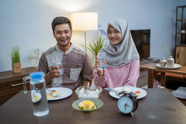 一对穆斯林夫妇早起去吃萨胡尔或苏胡尔的早餐作为禁食 显示时间的前置时钟 — 图库照片