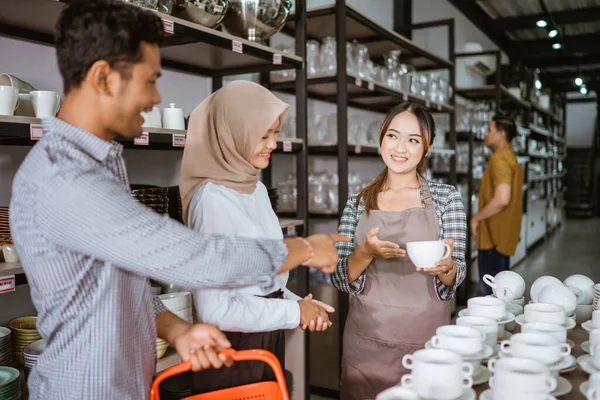 Female Shop Assistant Apron Holding Cup While Presenting Customer Couple — Fotografia de Stock