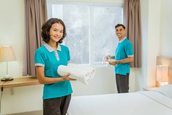 Smiling Female Housekeeper Turquoise Uniform Holding Towel Standing Hotel Room — стоковое фото