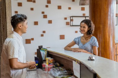 female guest asks the hotel receptionist before checking in at the lobby
