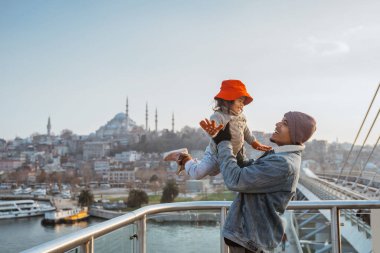 father and daughter travel to turkey. portrait of dad carrying his kid while enjoying the view of beautiful istanbul turkey from the bridge