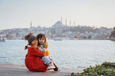 happy sister sitting down with the view of bosphorus sea and city of istanbul turkey