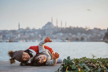 two sister playing and laying on the floor with beautiful background of istanbul city
