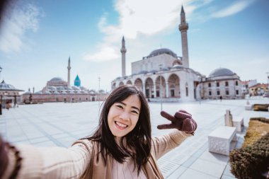 beautiful asian woman taking selfie portrait in front of the mosque in konya turkey