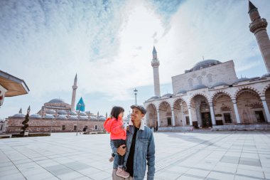 father and his little girl walking around the square in konya turkey enjoying the beautiful islamic architecture
