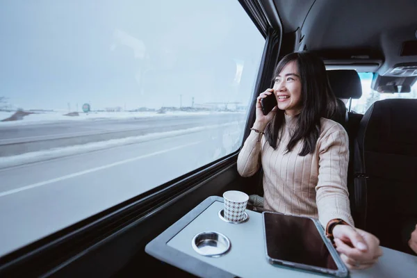 asian young woman making a phone call during her trip inside a van